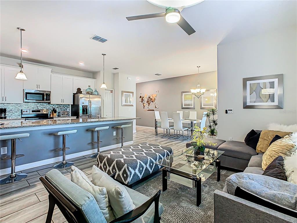 An open-concept kitchen, dining area, and living room featuring tile floors and modern furniture — 1579 MOON VALLEY DR, DAVENPORT, FL