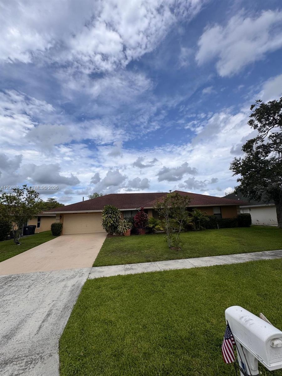 A single-story house with a brown roof, tan exterior, and a concrete driveway — 1800 Wisteria St, Wellington FL 33414, WELLINGTON, FL