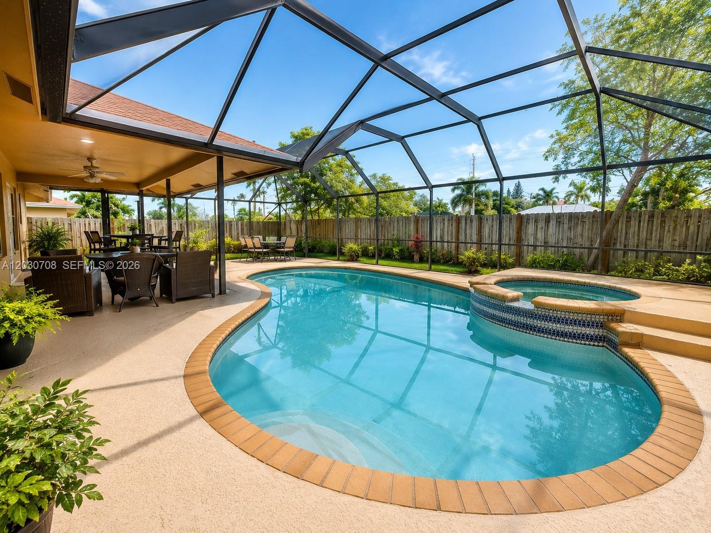 A screened-in patio features a swimming pool, a raised hot tub, and outdoor furniture — 1800 Wisteria St, Wellington FL 33414, WELLINGTON, FL