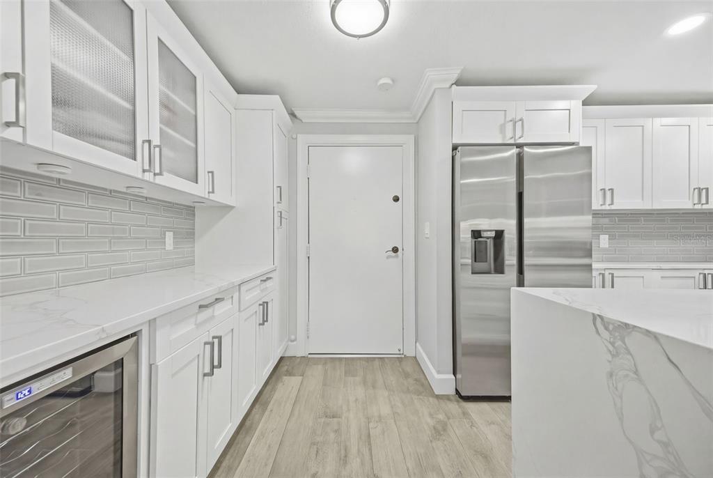 A modern kitchen features white cabinetry, stainless steel appliances, marble countertops, and light wood flooring — 4141 BAYSHORE BOULEVARD UNIT 306, TAMPA, FL