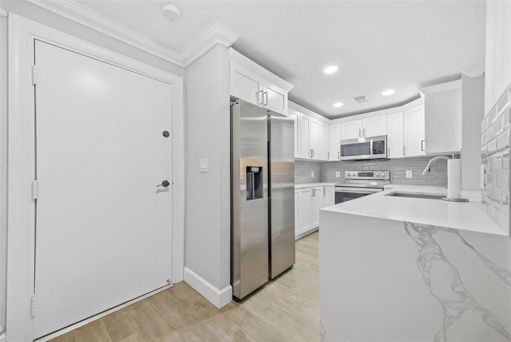 A modern kitchen features white cabinets, stainless steel appliances, and white marble-patterned countertops — 4141 BAYSHORE BOULEVARD UNIT 306, TAMPA, FL