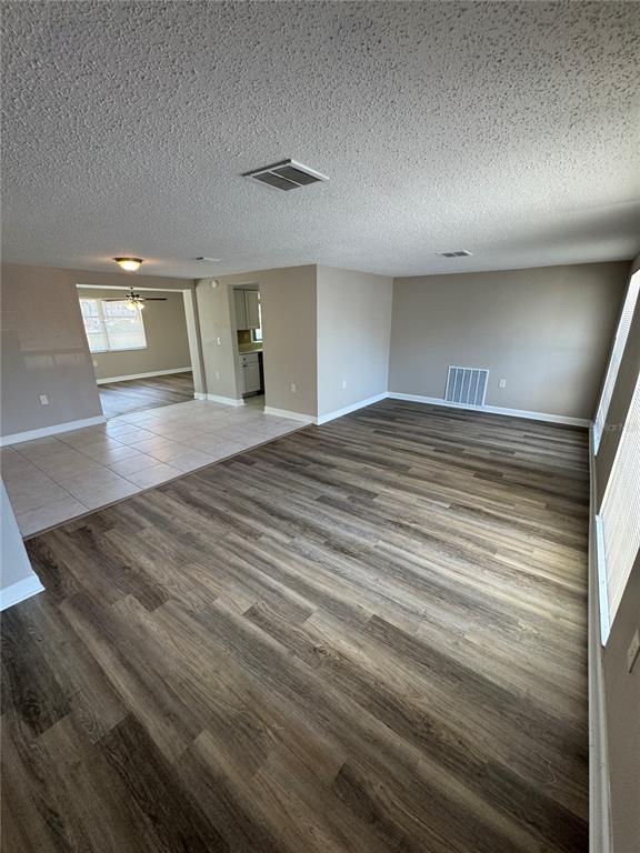 An open-concept living area features wood-look flooring, a tiled dining space, and neutral walls — 6135 SEABREEZE DRIVE, PORT RICHEY, FL