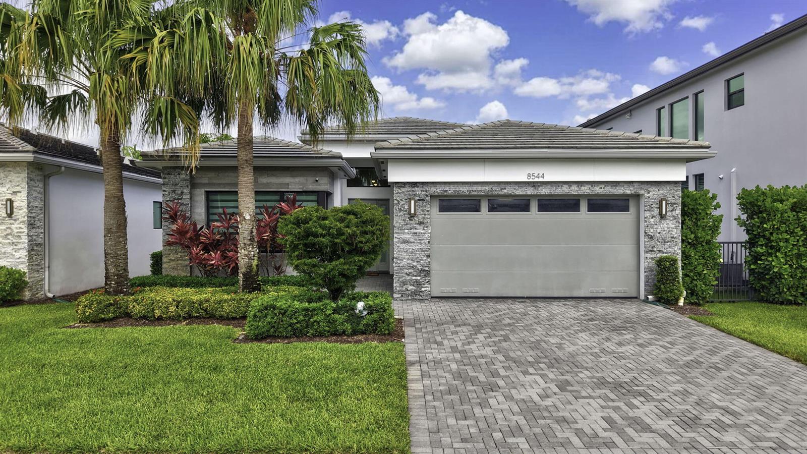 A single-story house with a gray stone facade, a two-car garage, and a palm tree — 8544 Apple Falls Lane, Boca Raton FL 33496, BOCA RATON, FL