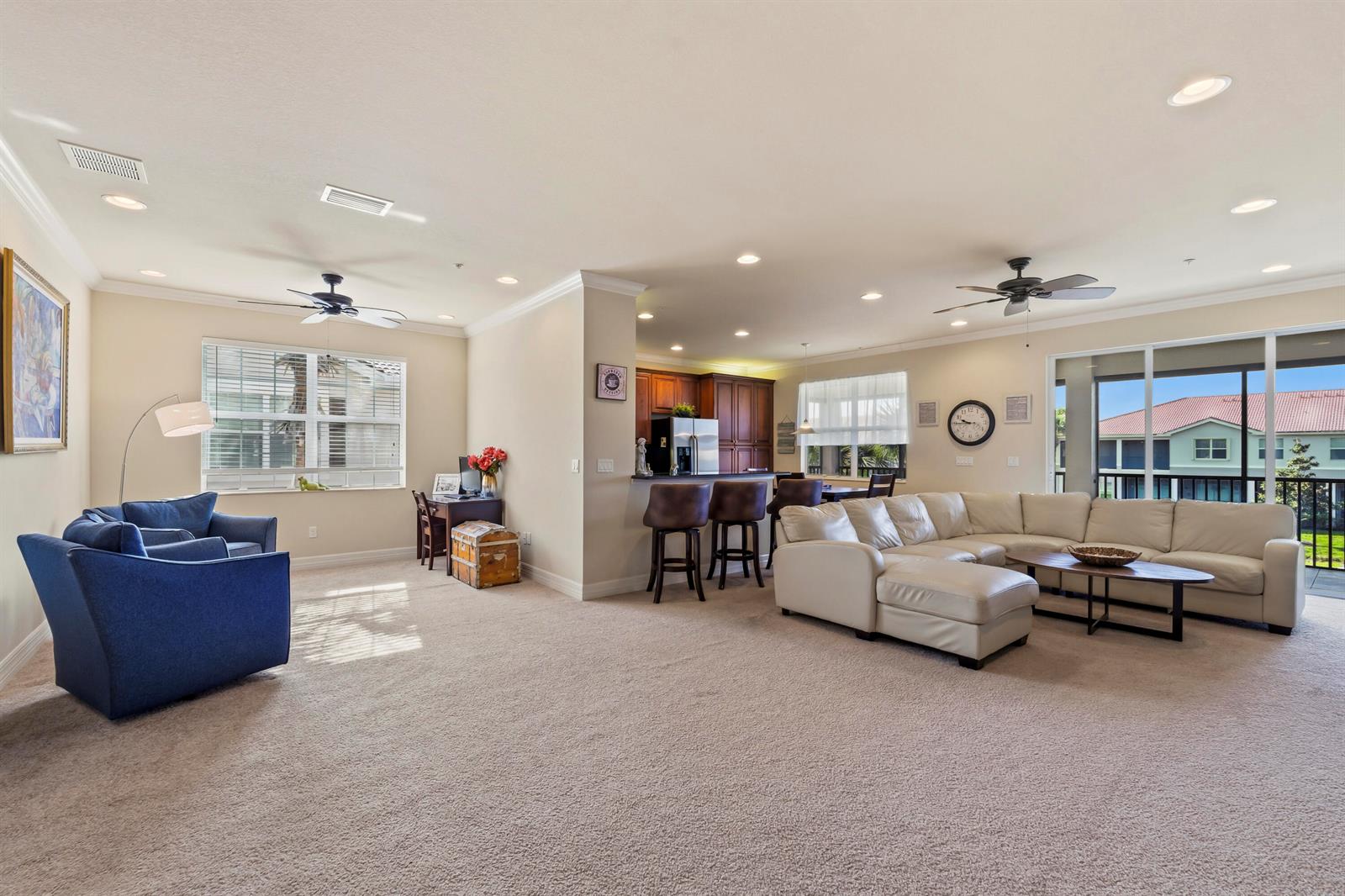 A spacious living room features a sectional sofa, blue armchairs, and an open kitchen area — 6513 Monterey Point # 201, Naples FL 34105, NAPLES, FL