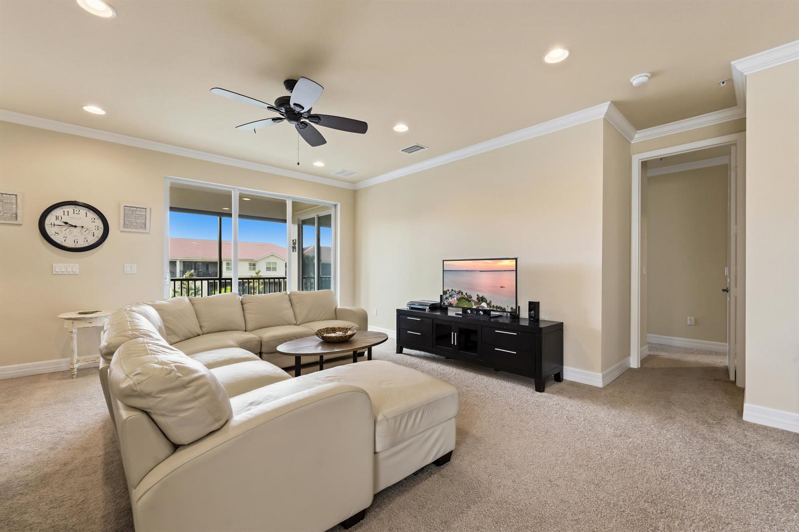 A living room features a beige sectional sofa, a black media console, and a ceiling fan — 6513 Monterey Point # 201, Naples FL 34105, NAPLES, FL