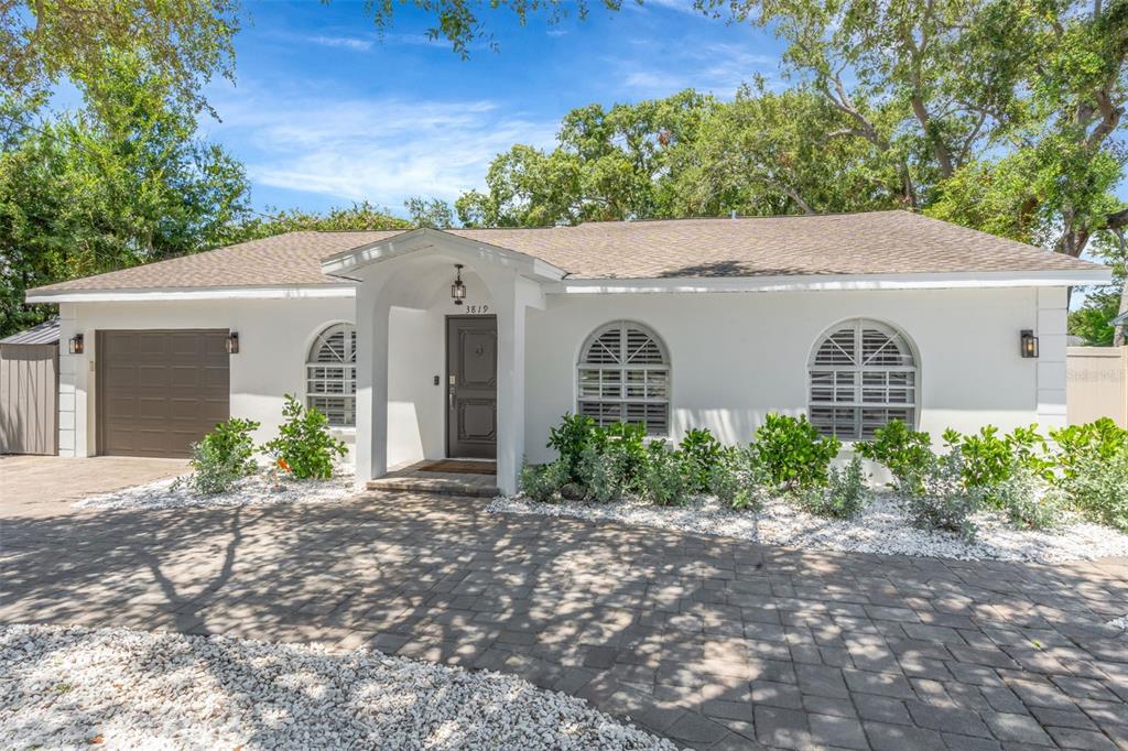 A single-story white house with a brown garage door and arched windows under a roof — 3819 W SAN MIGUEL STREET, TAMPA, FL