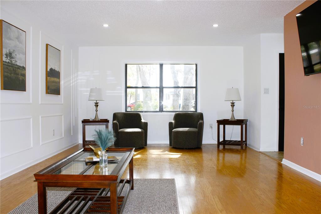 A living room features two armchairs, side tables with lamps, and a glass-topped coffee table — 3201 BARTLETT STREET, SPRING HILL, FL