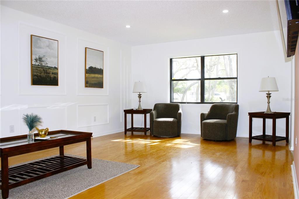 A living room features hardwood floors, two armchairs, side tables with lamps, and framed artwork — 3201 BARTLETT STREET, SPRING HILL, FL