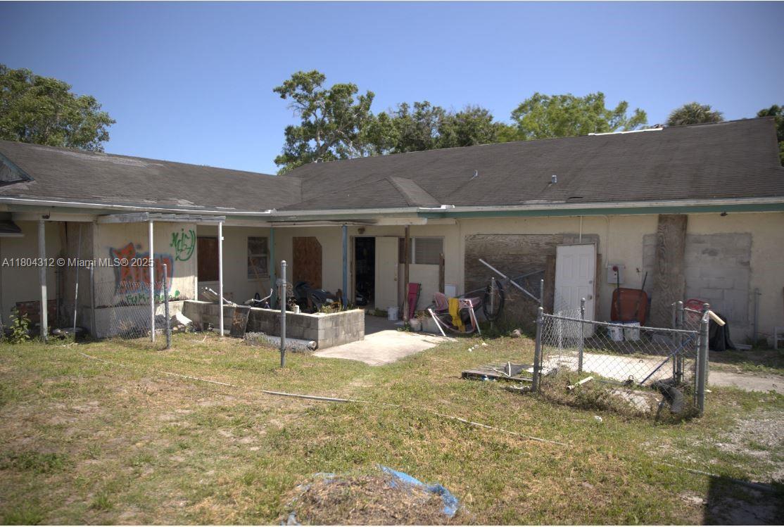 The exterior of a single-story house features a weathered facade, boarded windows, and a chain-link fence — 603 S 33rd St, Fort Pierce FL 34947, FORT PIERCE, FL