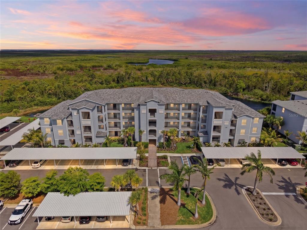 An aerial view shows a multi-story apartment building with covered parking and surrounding landscaping — 14151 HERITAGE LANDING BOULEVARD UNIT 1011, PUNTA GORDA, FL