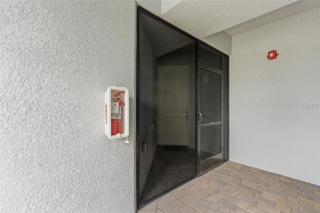 An exterior view of a building entrance featuring a screen door and a fire extinguisher — 14151 HERITAGE LANDING BOULEVARD UNIT 1011, PUNTA GORDA, FL