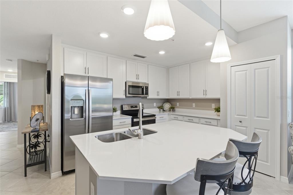 A modern kitchen features white cabinets, stainless steel appliances, and a large central island — 14151 HERITAGE LANDING BOULEVARD UNIT 1011, PUNTA GORDA, FL
