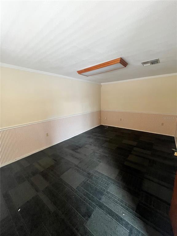 An empty room features dark carpet, light-colored walls with wainscoting, and a rectangular ceiling light — 7218 CONGRESS ST., NEW PORT RICHEY, FL