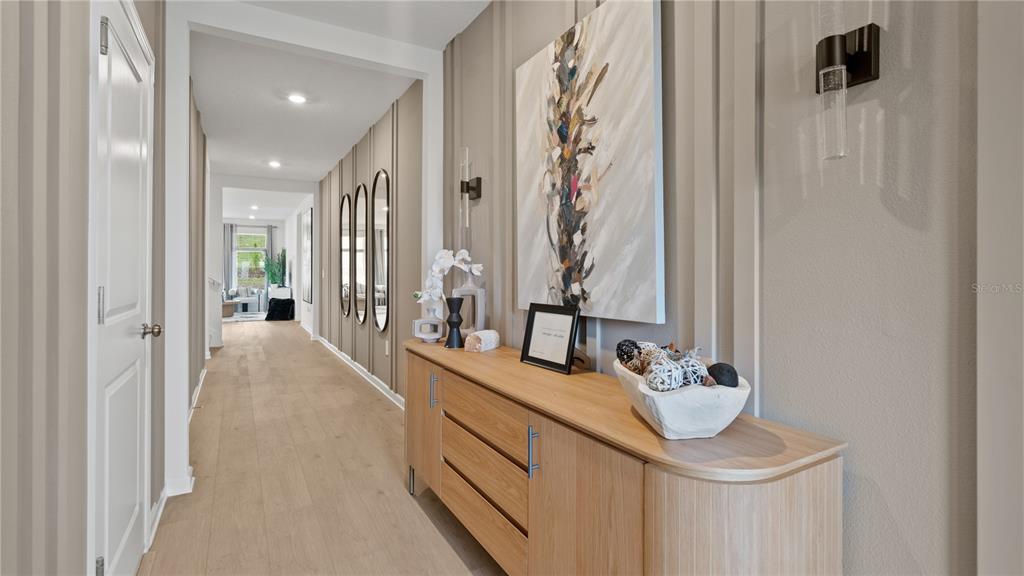 A hallway features light wood flooring, vertical wall paneling, and a wooden console table — 2214 JENNIO DRIVE, HAINES CITY, FL