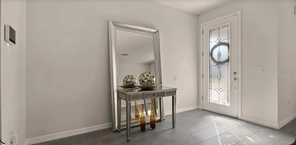 An entryway features a mirrored console table, a large floor mirror, and a glass-paneled door — 17243 GOLDCREST LOOP, CLERMONT, FL