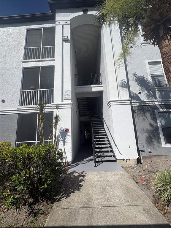 An exterior view of a multi-story apartment building with a central staircase and balconies — 5821 LEGACY CRESCENT PLACE UNIT 102, RIVERVIEW, FL
