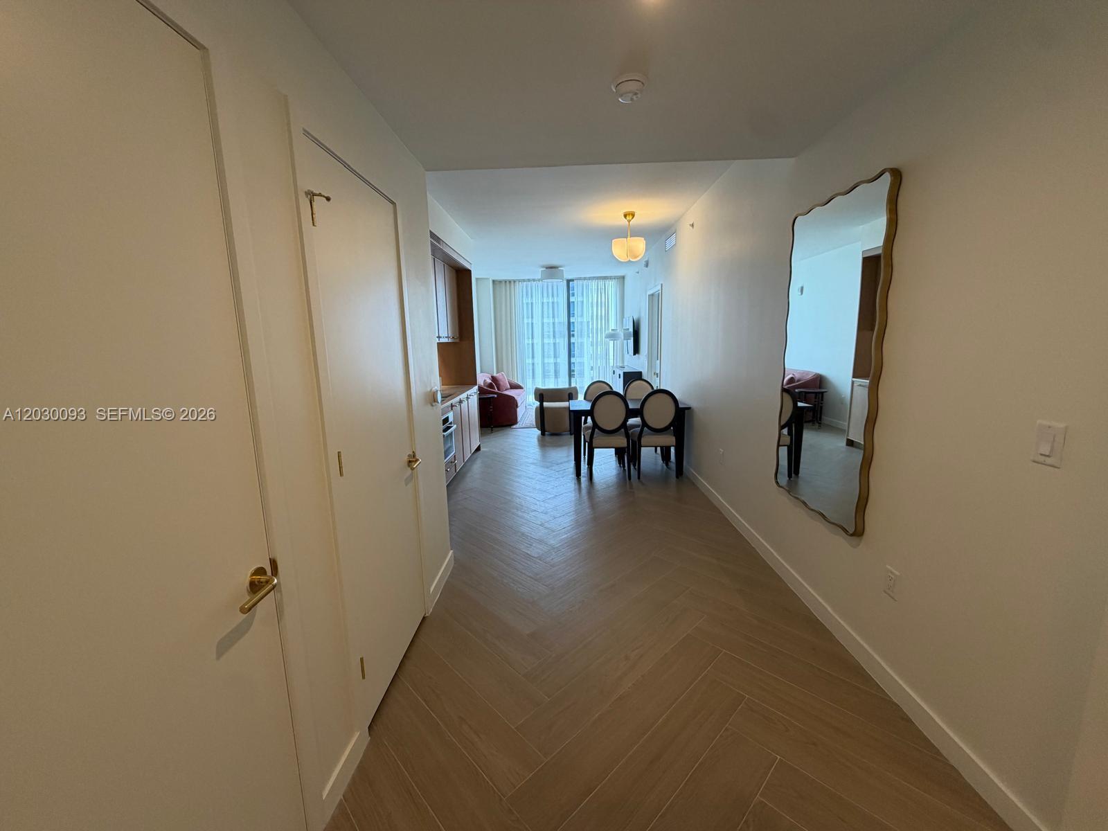 A hallway with herringbone wood flooring leads to an open-concept dining and living area — 2700 NW 2ND AVE # 342, Miami FL 33127, MIAMI, FL