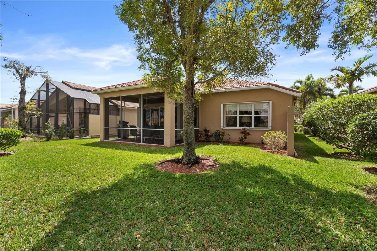 A tan house with a screened-in lanai and a large tree in the backyard — 8839 Via Avellino, Lake Worth FL 33467, LAKE WORTH, FL