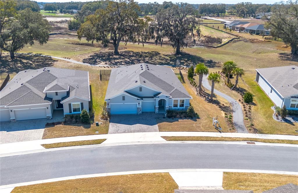An aerial view shows three suburban houses with gray roofs along a curved street — 5220 NW 46TH LANE ROAD, OCALA, FL