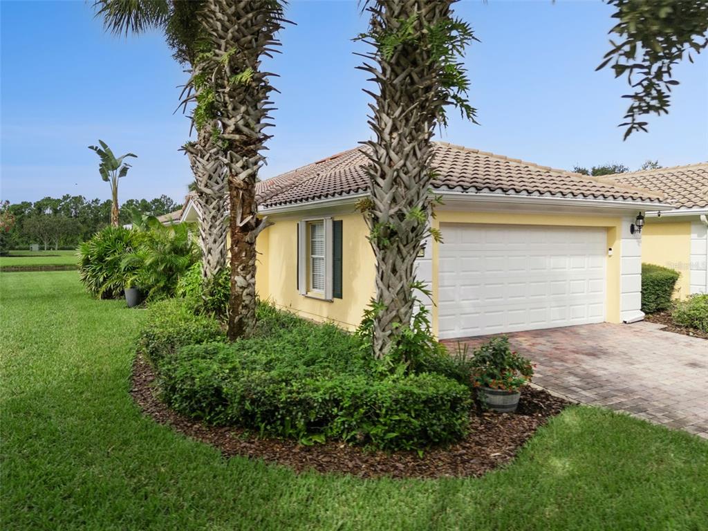A yellow house with a white garage door and two palm trees in the front yard — 12004 KAJETAN LANE, ORLANDO, FL