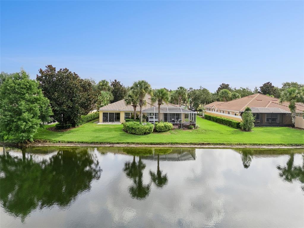 A view of a single-story house with a screened lanai overlooking a pond — 12004 KAJETAN LANE, ORLANDO, FL