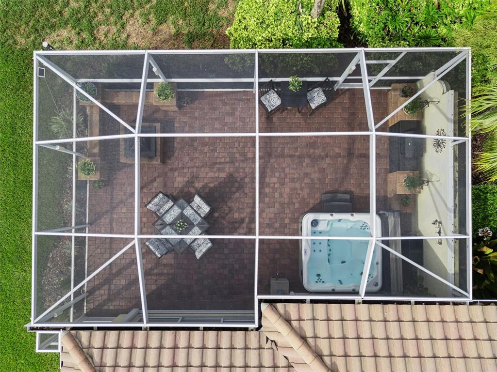 An aerial view of a screened-in patio featuring a hot tub, dining set, and pavers — 12004 KAJETAN LANE, ORLANDO, FL