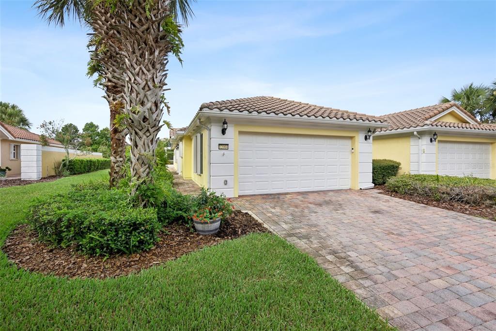 A single-story house with a white garage door, yellow siding, and a paver driveway — 12004 KAJETAN LANE, ORLANDO, FL
