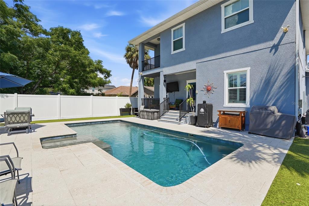 A blue two-story house features a backyard swimming pool with a patio and white fence — 6709 INTERBAY BOULEVARD, TAMPA, FL