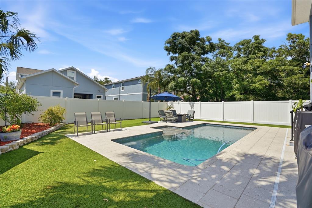 A backyard features a rectangular swimming pool, patio furniture, artificial turf, and a white fence — 6709 INTERBAY BOULEVARD, TAMPA, FL