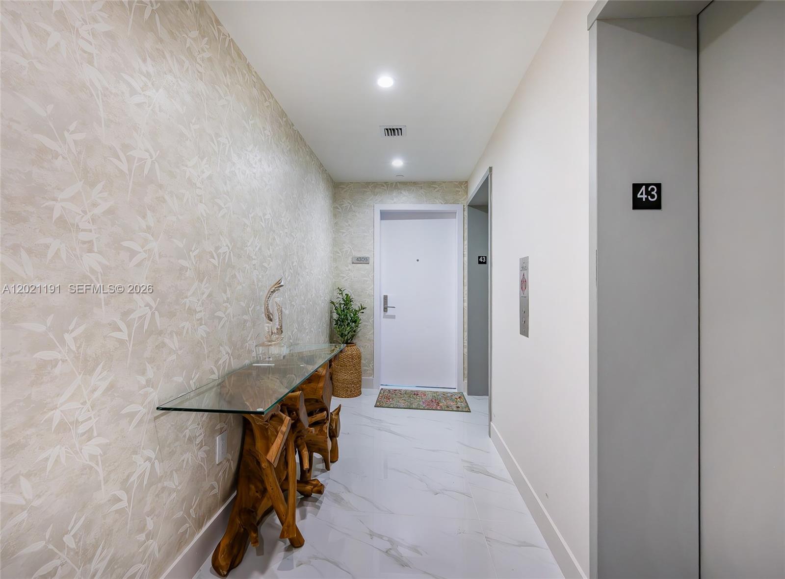 A hallway features marble floors, patterned wallpaper, and a glass-topped wooden console table — 700 NE 24th Street, Miami FL 33137, MIAMI, FL