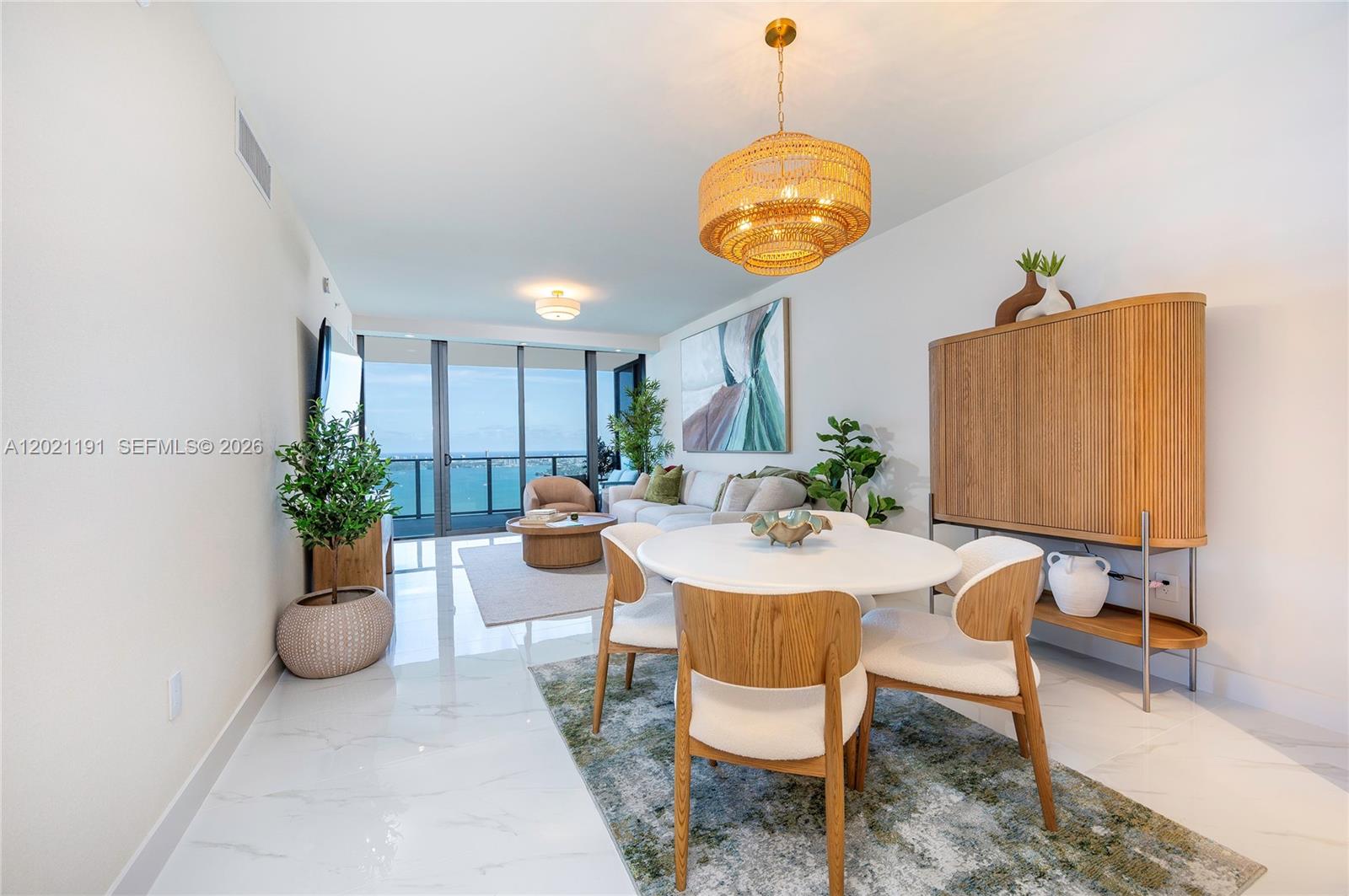 A dining and living area features white marble floors, a round table, and ocean views — 700 NE 24th Street, Miami FL 33137, MIAMI, FL