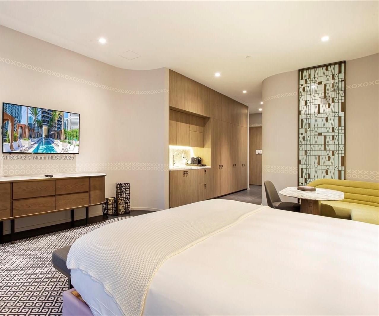 A bedroom features a television, a small kitchenette, and a curved wall with decorative patterns — 801 S Miami Ave # 611, Miami FL 33130, MIAMI, FL
