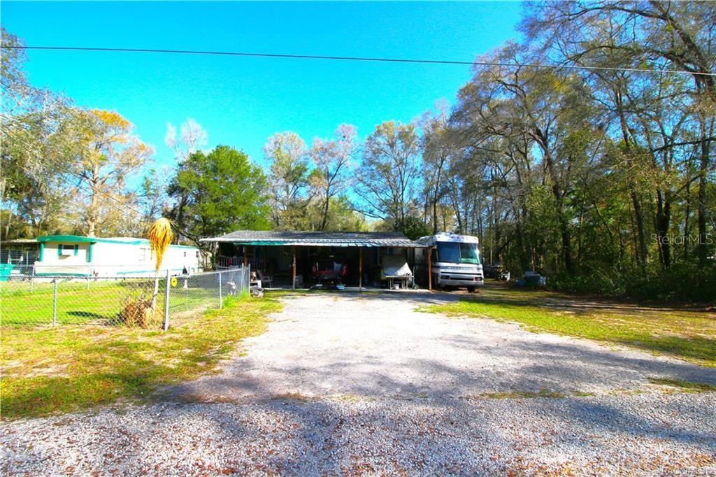 A gravel driveway leads to a covered carport area next to a parked recreational vehicle — 4629 E BOW N ARROW LOOP, INVERNESS, FL