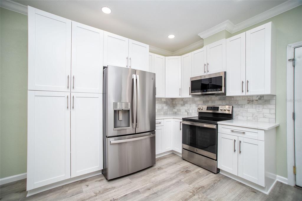 A kitchen with white cabinets, stainless steel appliances, and a marble-style tile backsplash — 415 DR ML KING JR STREET N, SAFETY HARBOR, FL