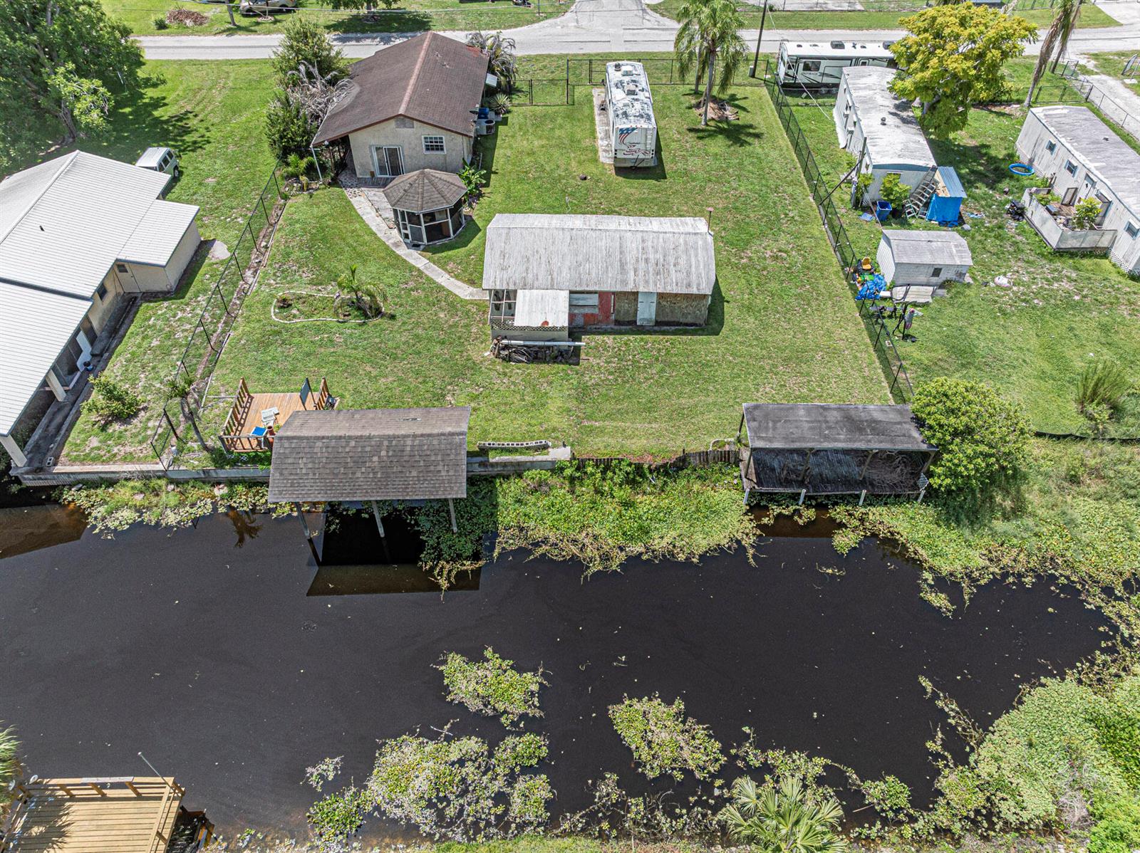 An aerial view shows a waterfront property with multiple buildings, a dock, and a canal — 1040 Lissie Lane, Okeechobee FL 34974, OKEECHOBEE, FL