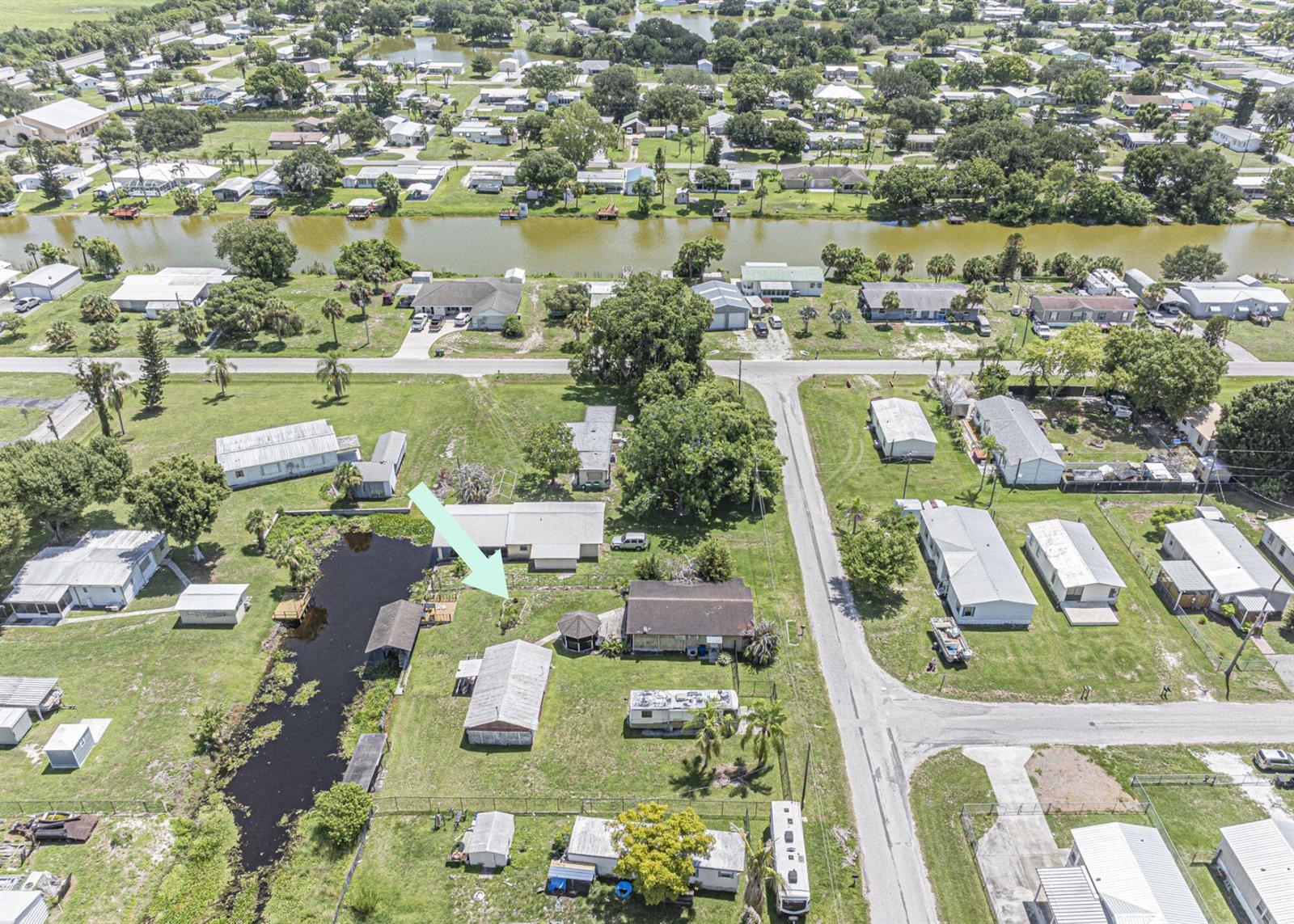 An aerial view shows a residential property with multiple structures, a pond, and surrounding homes — 1040 Lissie Lane, Okeechobee FL 34974, OKEECHOBEE, FL