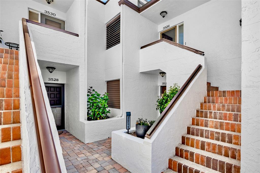 Exterior view of a multi-level apartment complex with brick stairs and white stucco walls — 3526 RICHWOOD LINK UNIT 48, SARASOTA, FL