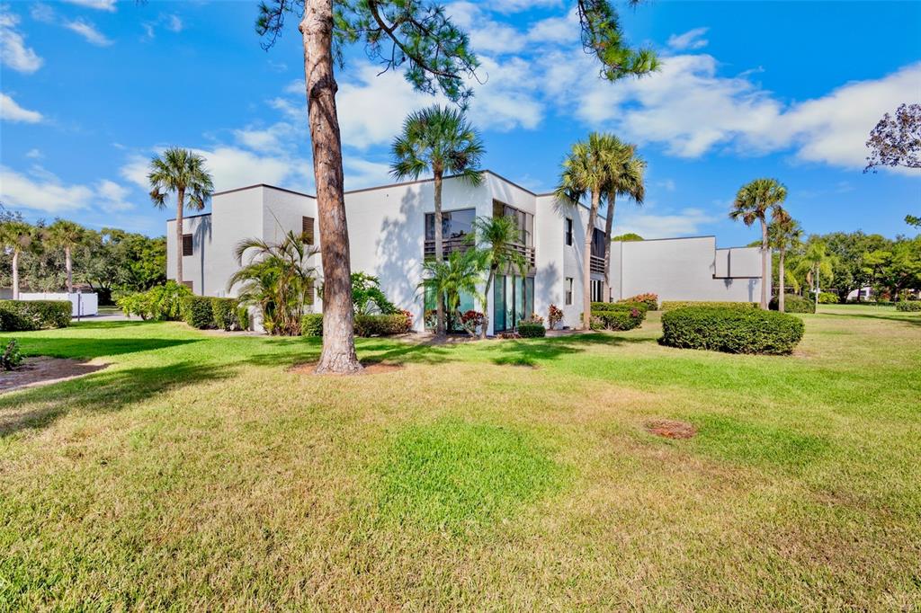 A two-story white building with flat roofs sits on a grassy lawn with palm trees — 3526 RICHWOOD LINK UNIT 48, SARASOTA, FL