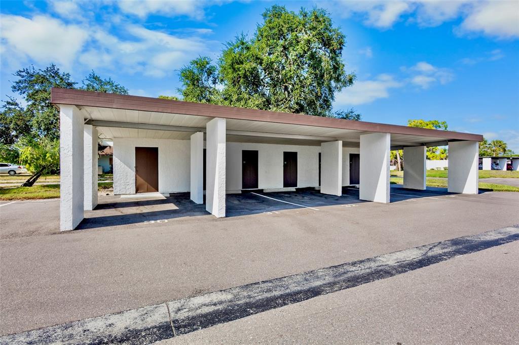 A covered parking structure with multiple storage units and white support pillars in a parking lot — 3526 RICHWOOD LINK UNIT 48, SARASOTA, FL