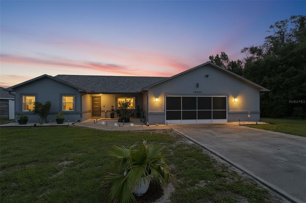 A single-story house with a gray exterior, a concrete driveway, and a screened garage door — 13323 STEVES COURT, SPRING HILL, FL