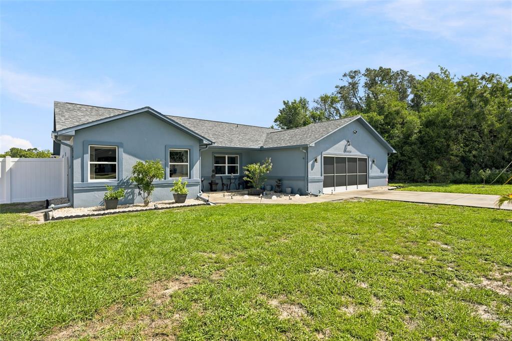 A blue single-story house features a two-car garage and a large grassy front yard — 13323 STEVES COURT, SPRING HILL, FL