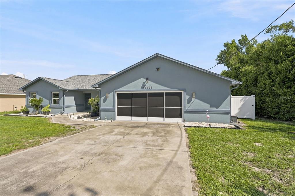 A single-story house with a gray exterior, a screened garage door, and a concrete driveway — 13323 STEVES COURT, SPRING HILL, FL