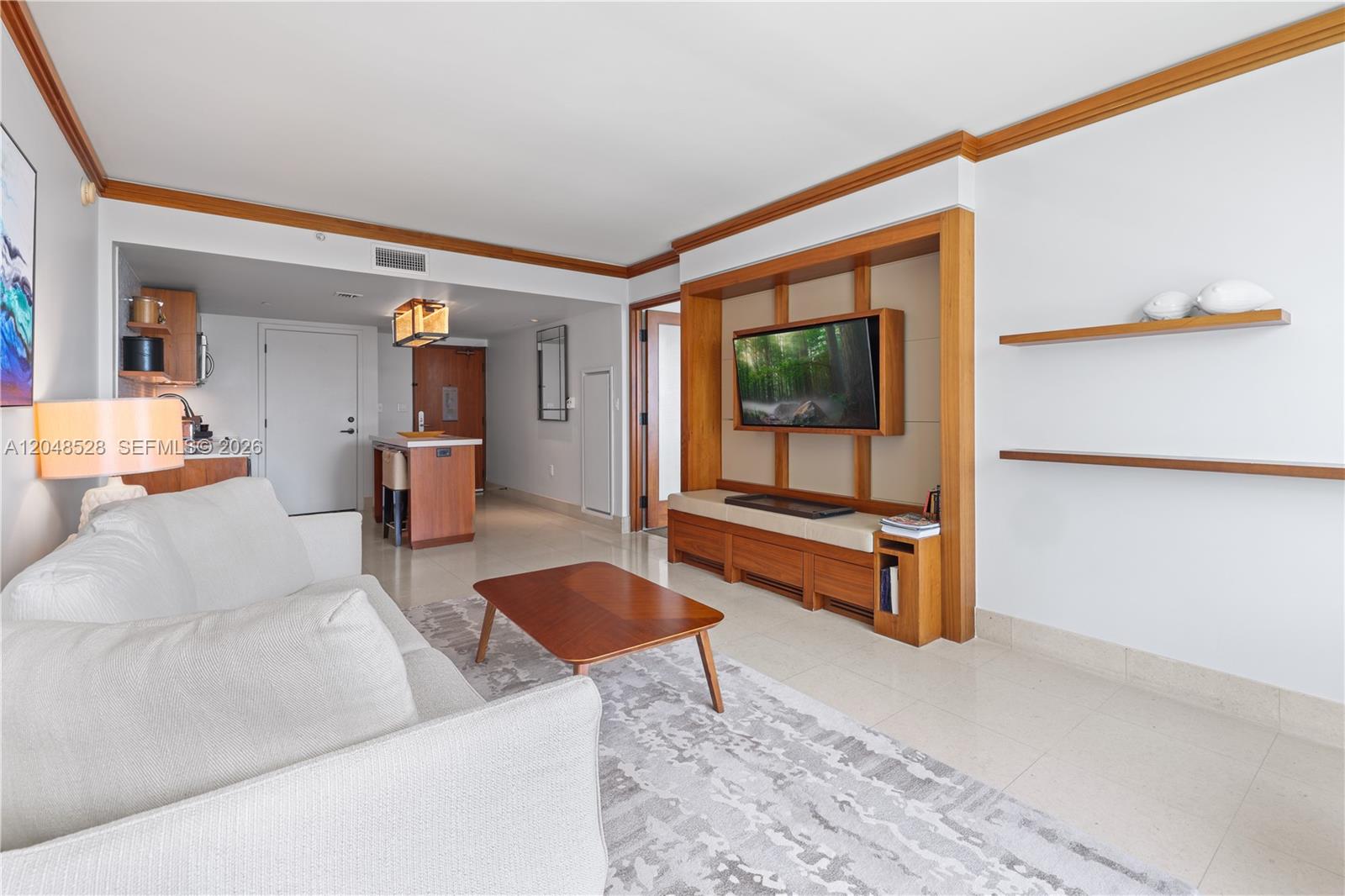 A living room features a white sofa, a wooden coffee table, and a built-in media unit — 6801 Collins Ave # 516, Miami Beach FL 33141, MIAMI BEACH, FL
