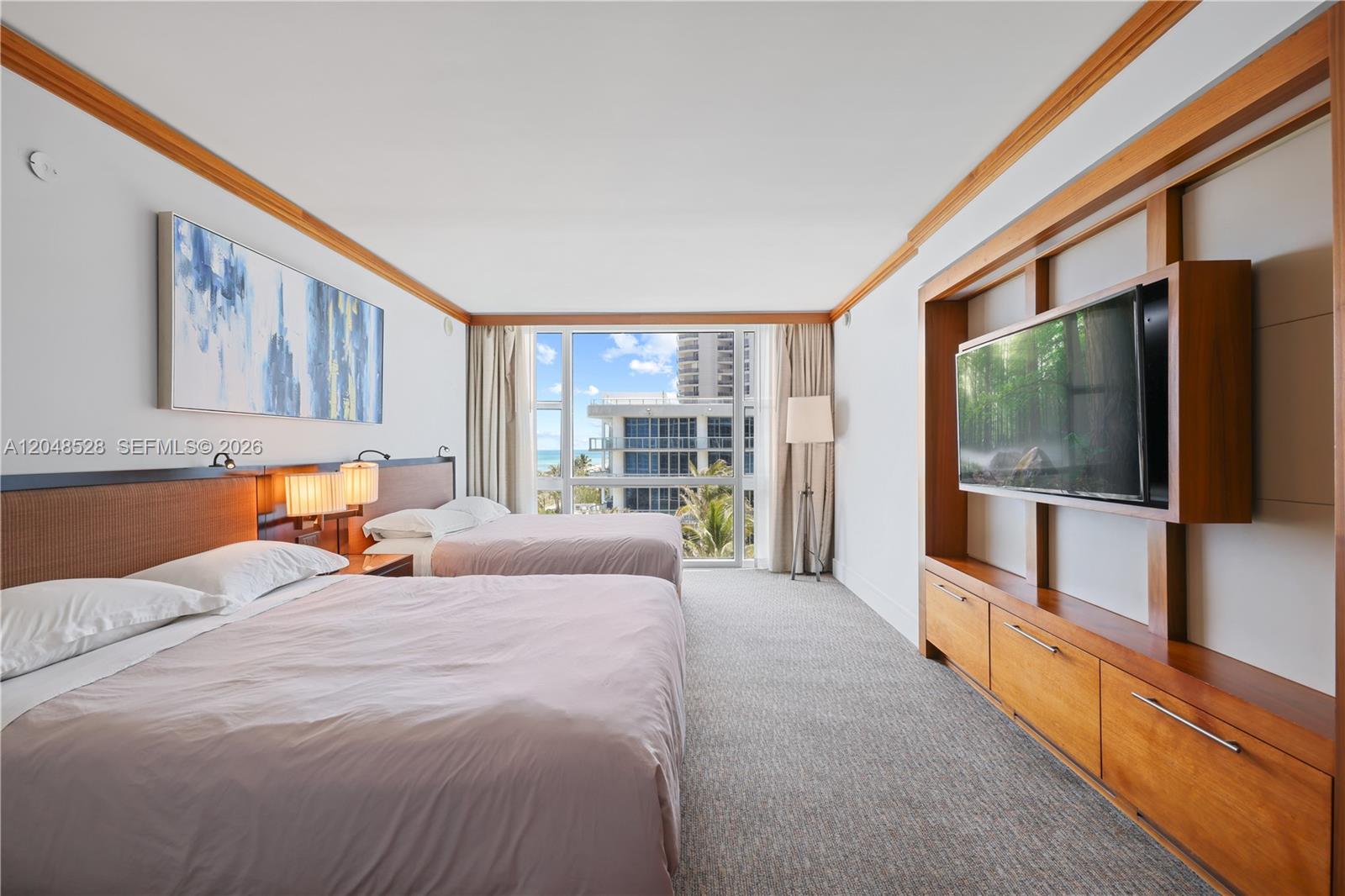 A hotel room features two beds, a wall-mounted television, and a window with ocean views — 6801 Collins Ave # 516, Miami Beach FL 33141, MIAMI BEACH, FL