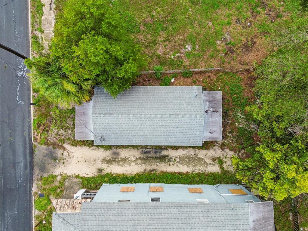 An aerial view shows two buildings with gray shingled roofs surrounded by trees and grass — 115 EMMA STREET, LAKELAND, FL