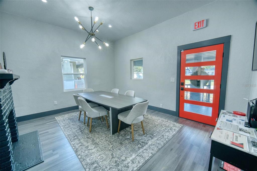 A conference room features a grey table, six chairs, a chandelier, and a bright orange door — 141 AVENUE E SW, WINTER HAVEN, FL