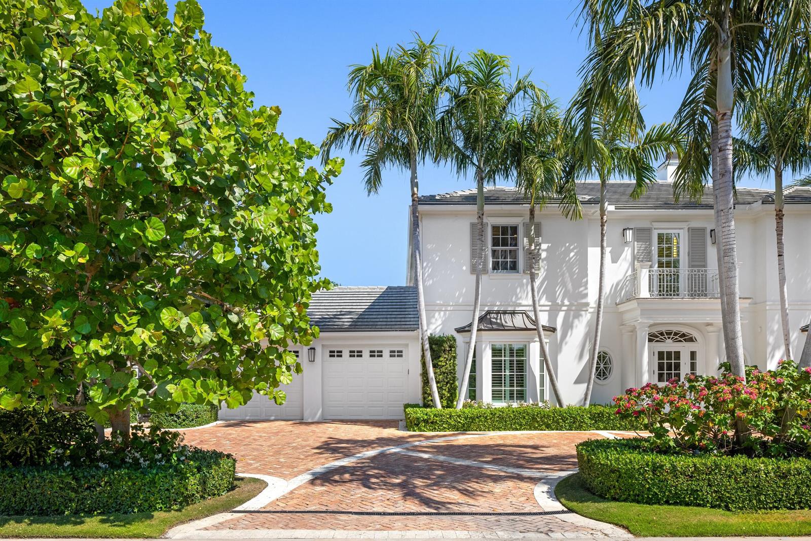 A white two-story house features a brick driveway, palm trees, and a manicured hedge — 211 Ocean Terrace, Palm Beach FL 33480, PALM BEACH, FL