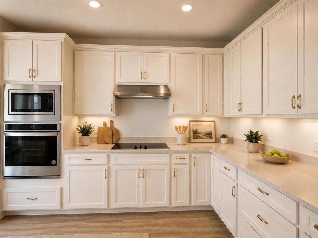A kitchen features white cabinetry, stainless steel appliances, a cooktop, and light-colored countertops — 2602 AUTUMN PEACE DRIVE, KISSIMMEE, FL