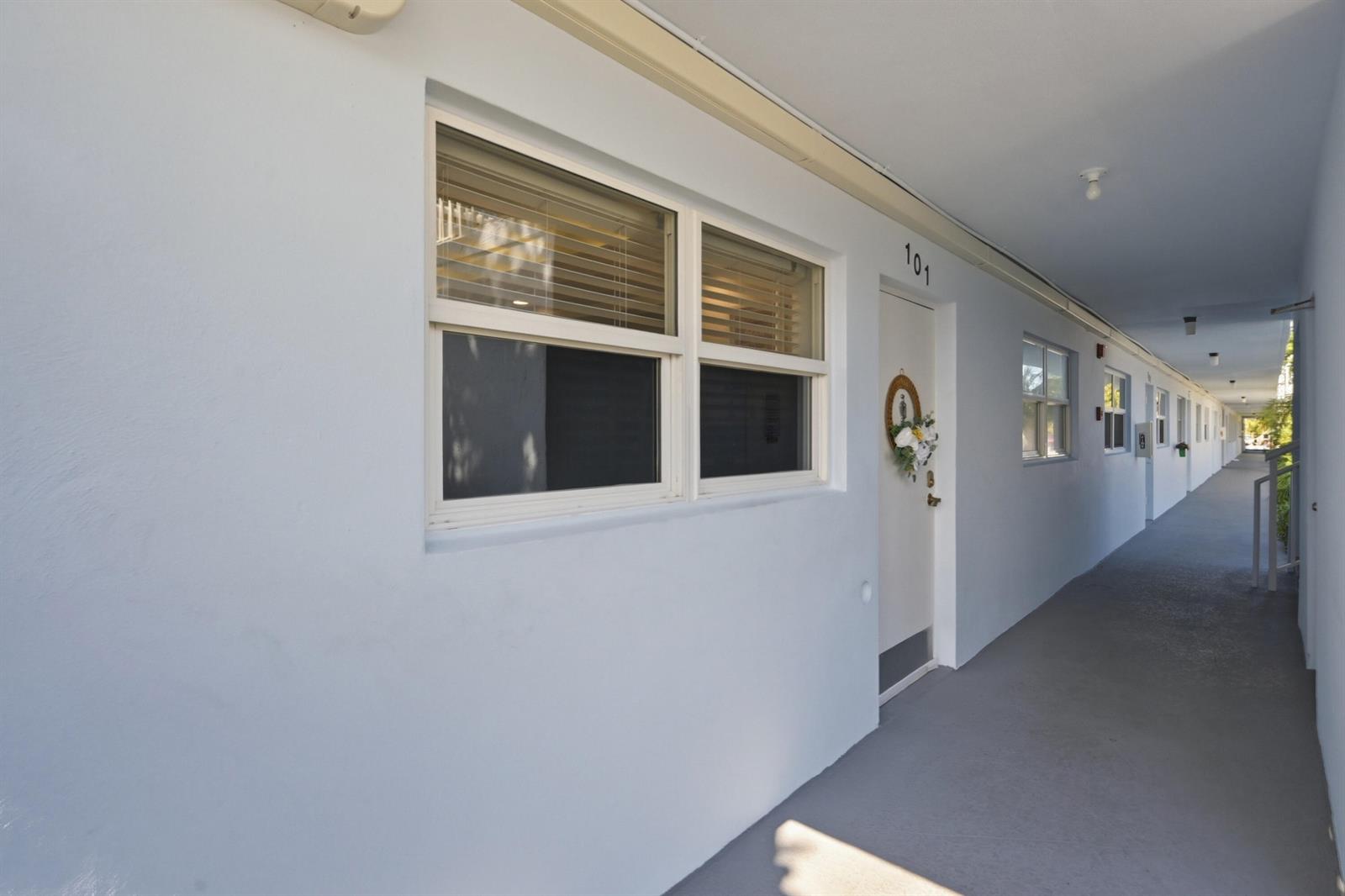 An exterior view of an apartment building hallway with a row of doors and windows — 2008 S Federal Highway # 101, Boynton Beach FL 33435, BOYNTON BEACH, FL