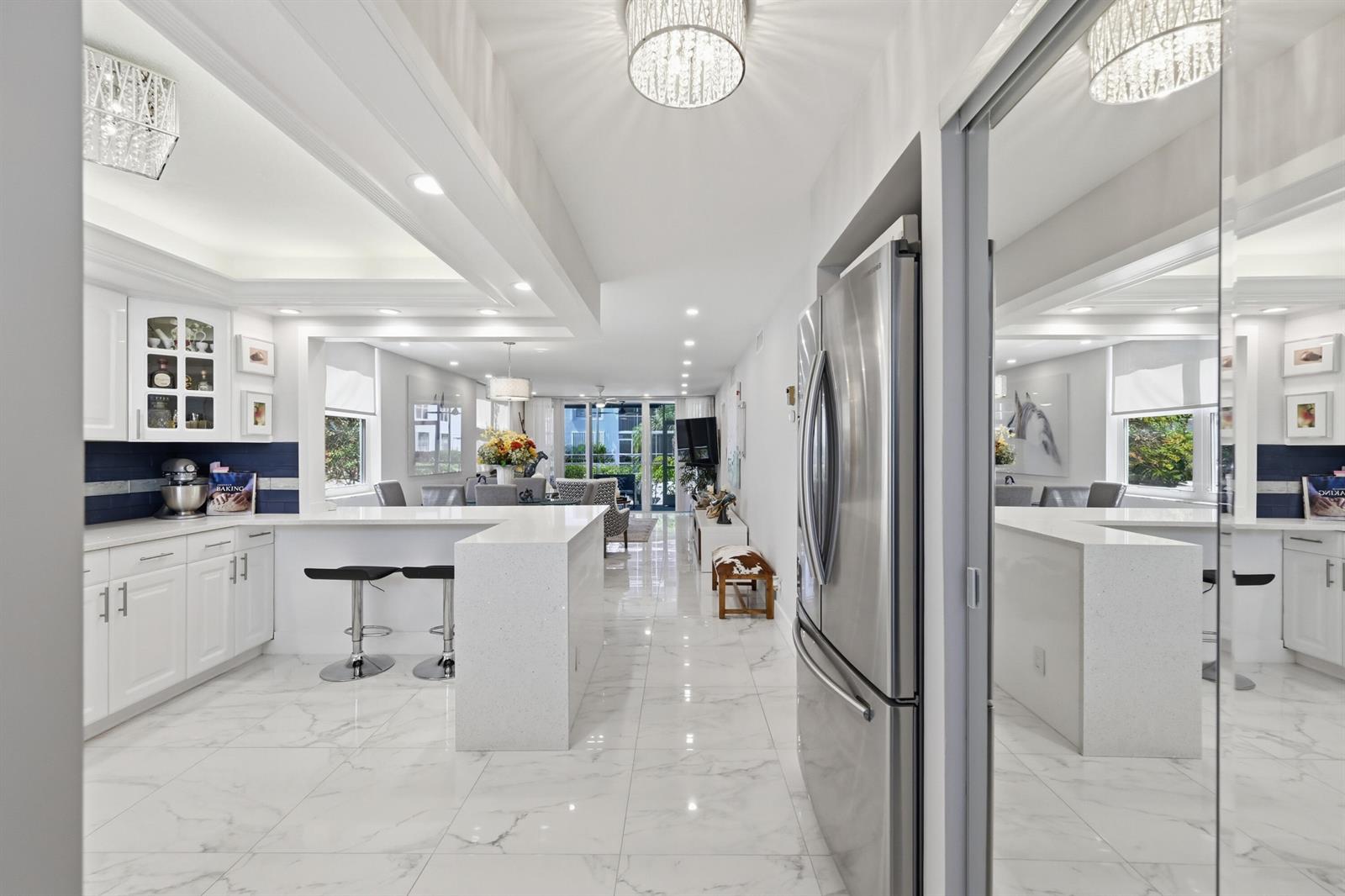 A modern kitchen with white cabinetry, quartz countertops, and marble flooring opens to a living area — 2008 S Federal Highway # 101, Boynton Beach FL 33435, BOYNTON BEACH, FL